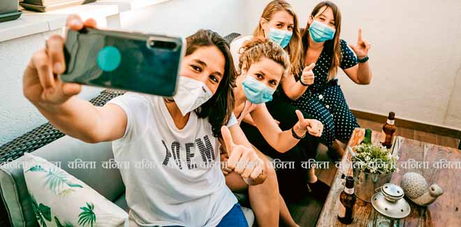 Group of young girlfriends meeting after the quarantine caused by the covid19. Taking precaution with surgical masks and taking photos together with a smartphone.