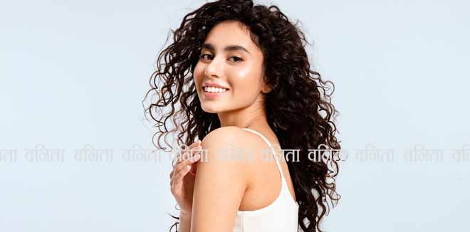 2323306519 A model girl with glowing skin and thick black and curly hair looks over her shoulder at the camera against a blue background