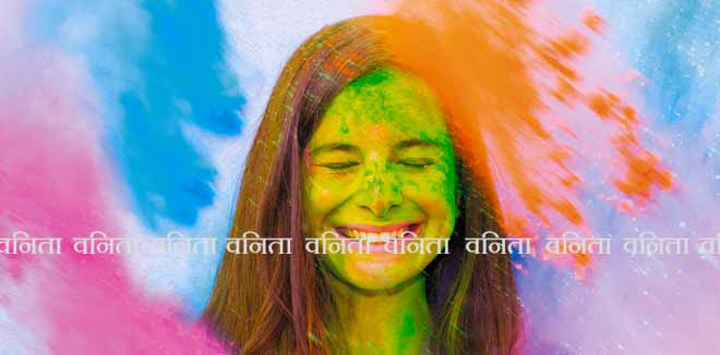Happy holi. Young cheerful girl under explosion of colored powder at Holi colors (paints) party. Freeze motion (stop motion) of color powder exploding or throwing colour powder. Glitter explosion.