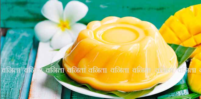 582897244 Mango pudding, jelly on white plate with palm leaf. Colorful wooden background.