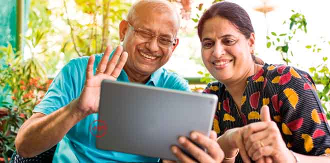 family-time Indian/asian Senior couple video chatting on tablet/computer while sitting at couch or in garden at home, selective focus