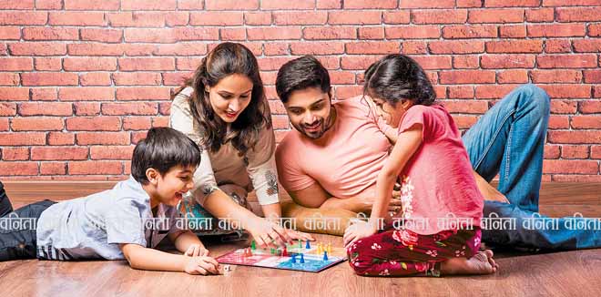 Indian young family of four playing board games like Chess, Ludo or Snack and Ladder at home in quarantine